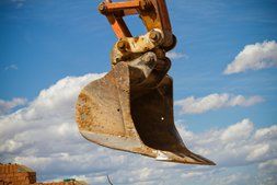 Picture of an excavator claw against the blue sky. 