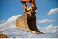 Picture of an excavator claw against the blue sky. 