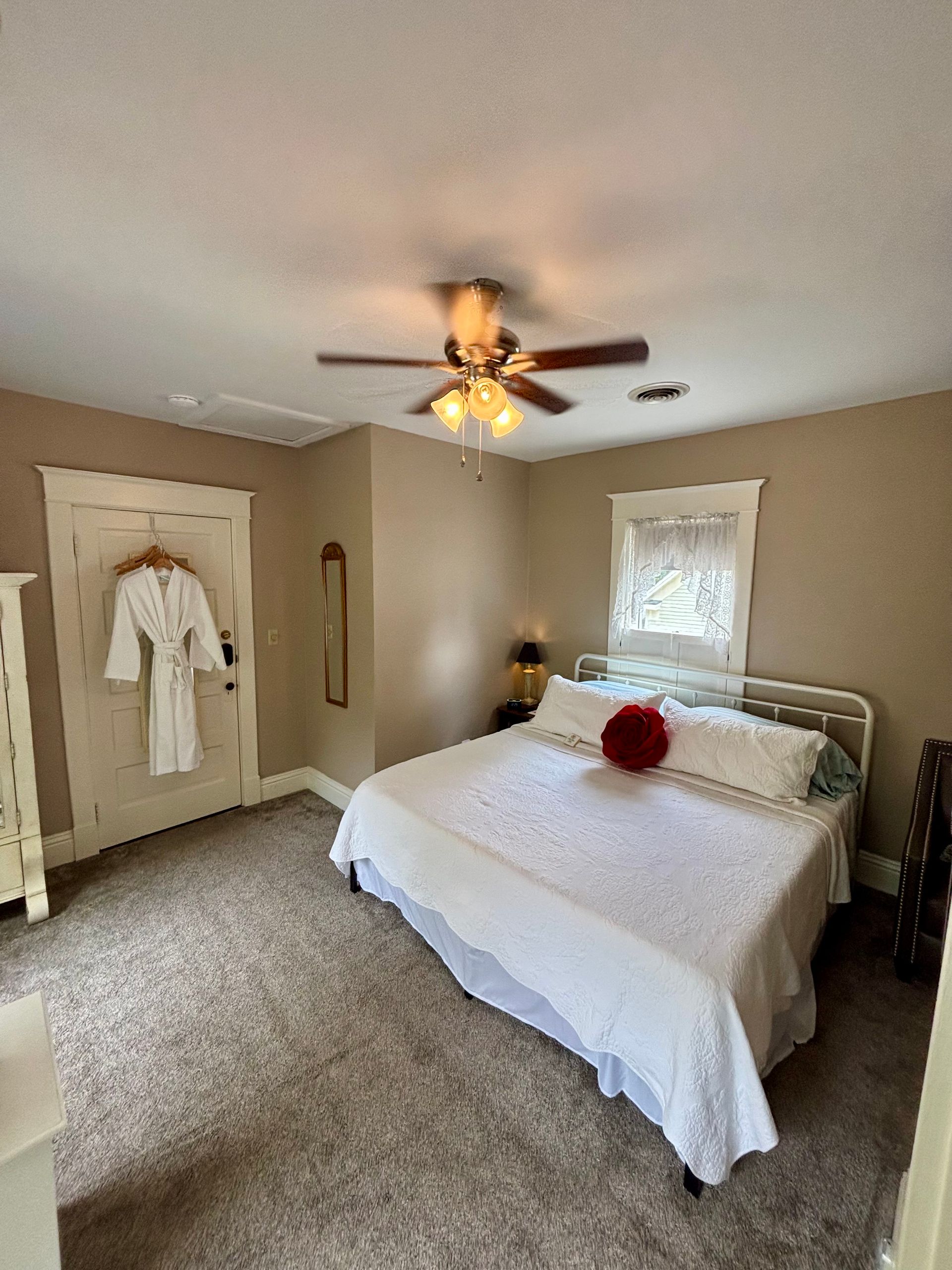 A bedroom with yellow walls and a ceiling fan.
