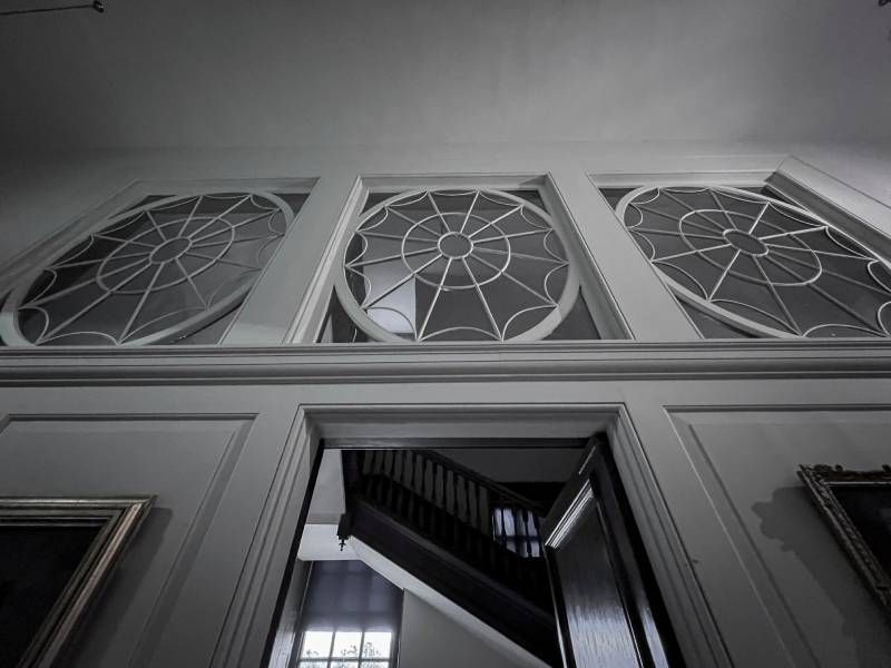 A black and white photo of a staircase with stained glass windows.