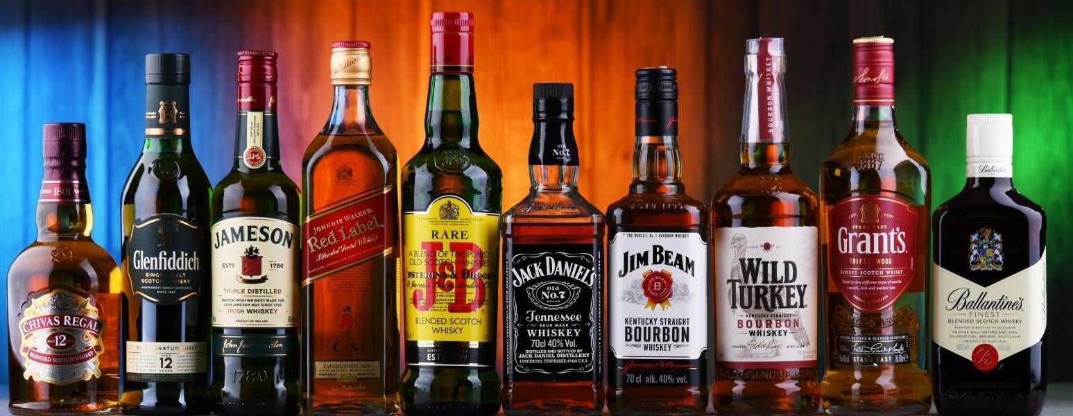 A row of bottles of whiskey are lined up on a table.