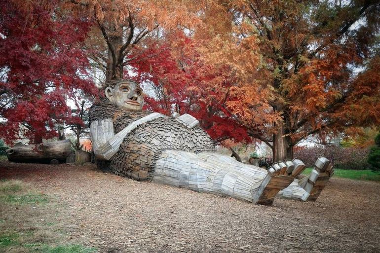 A statue of a giant laying on the ground in a park.