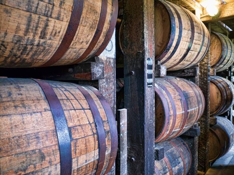 A row of wooden barrels stacked on top of each other in a warehouse.