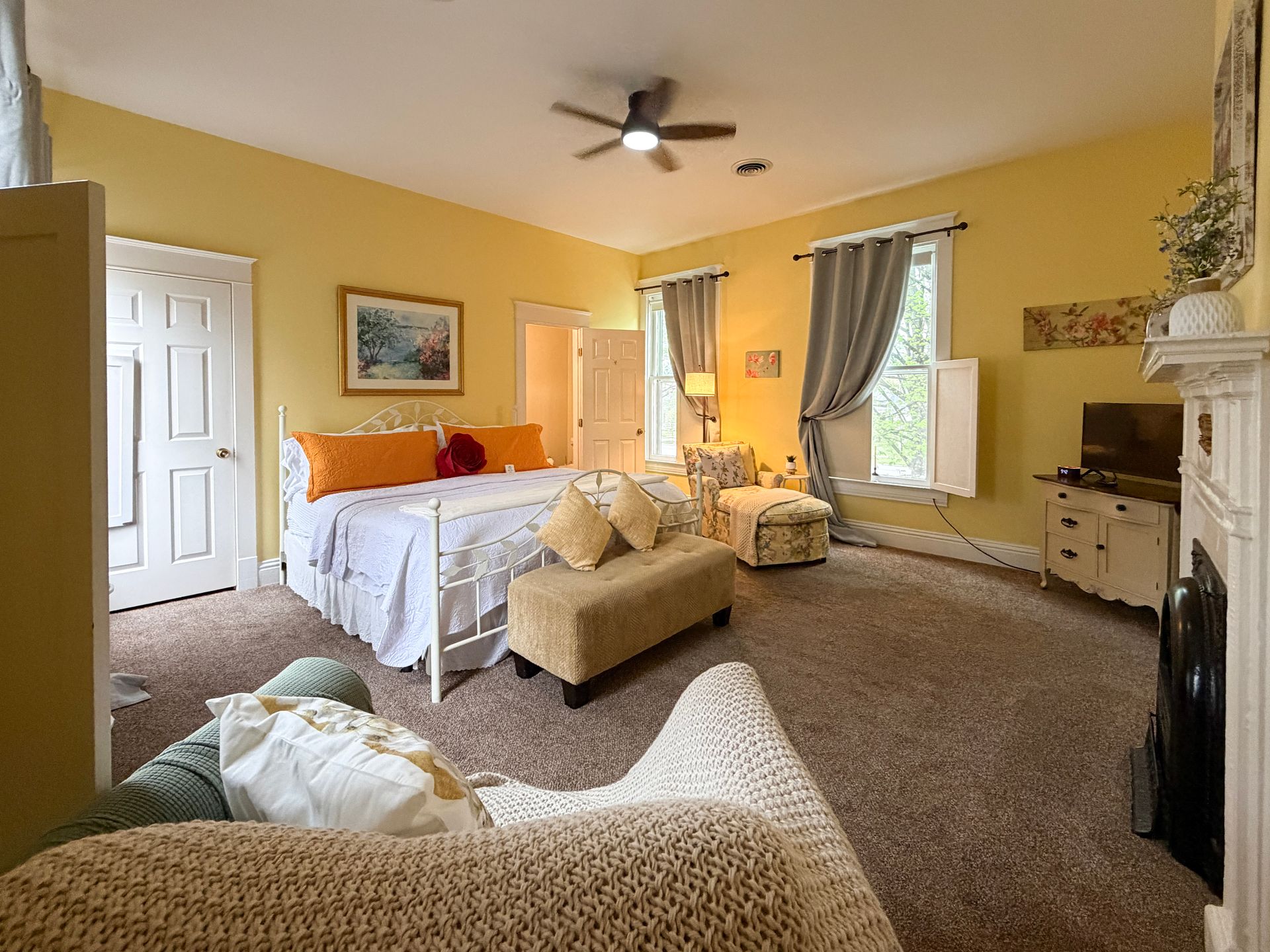 A bedroom with yellow walls and a ceiling fan.