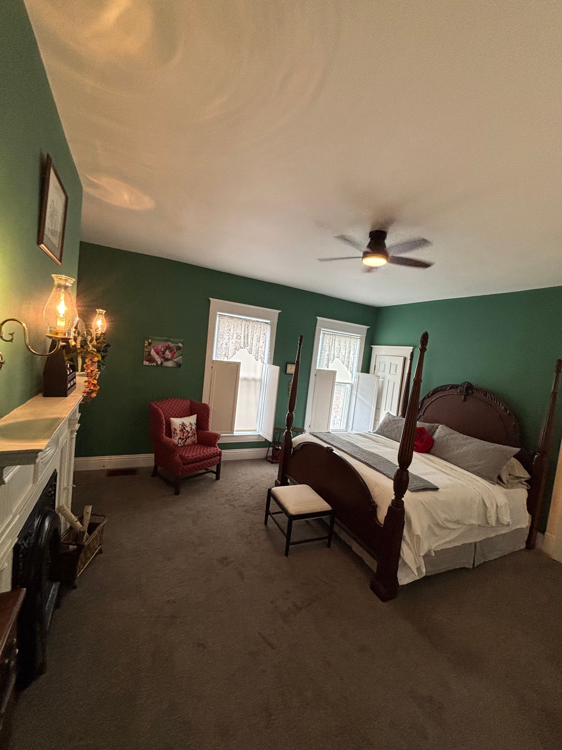 A bedroom with green walls and a four poster bed
