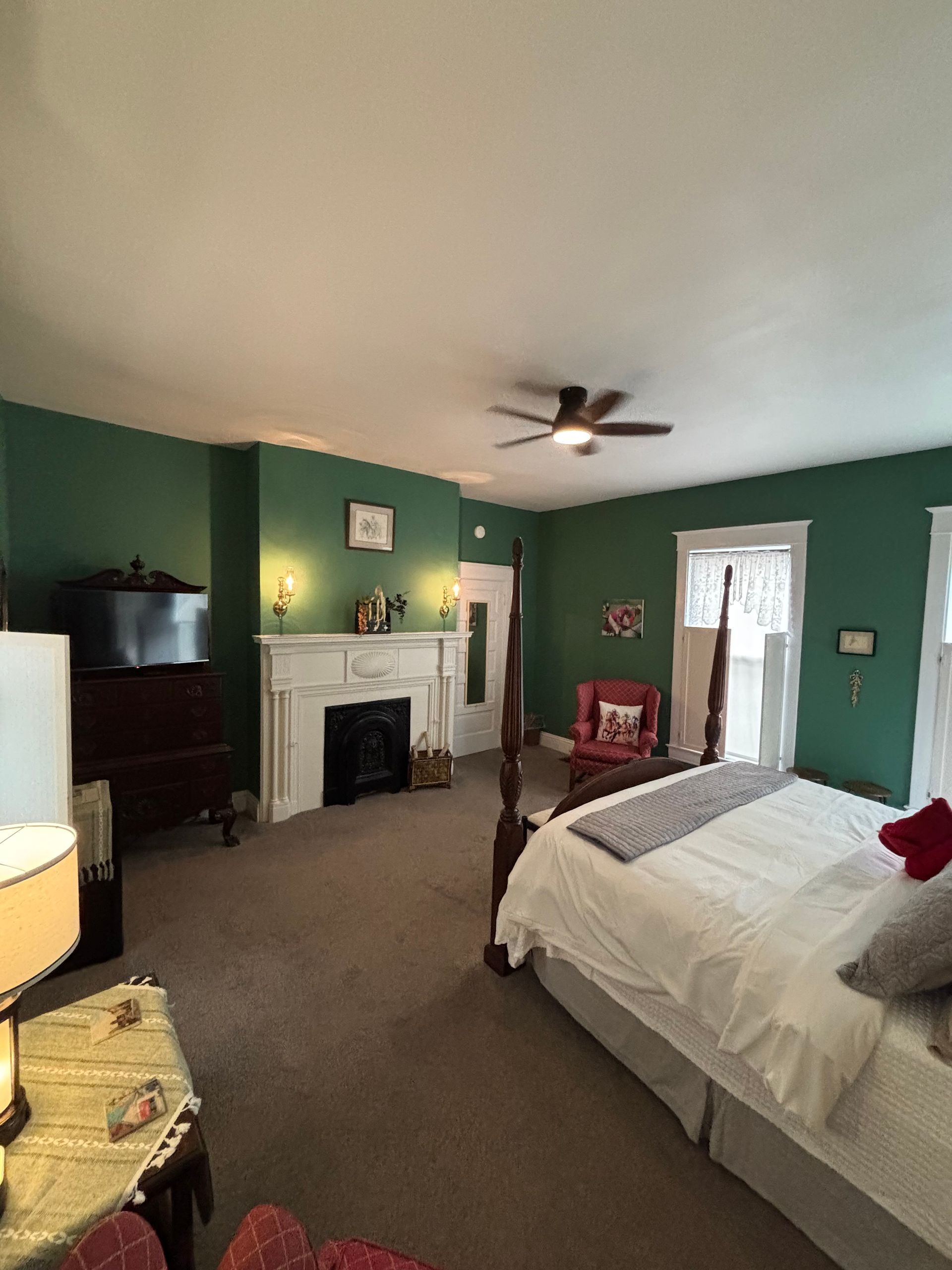 A bedroom with a four poster bed , chairs and a fireplace.