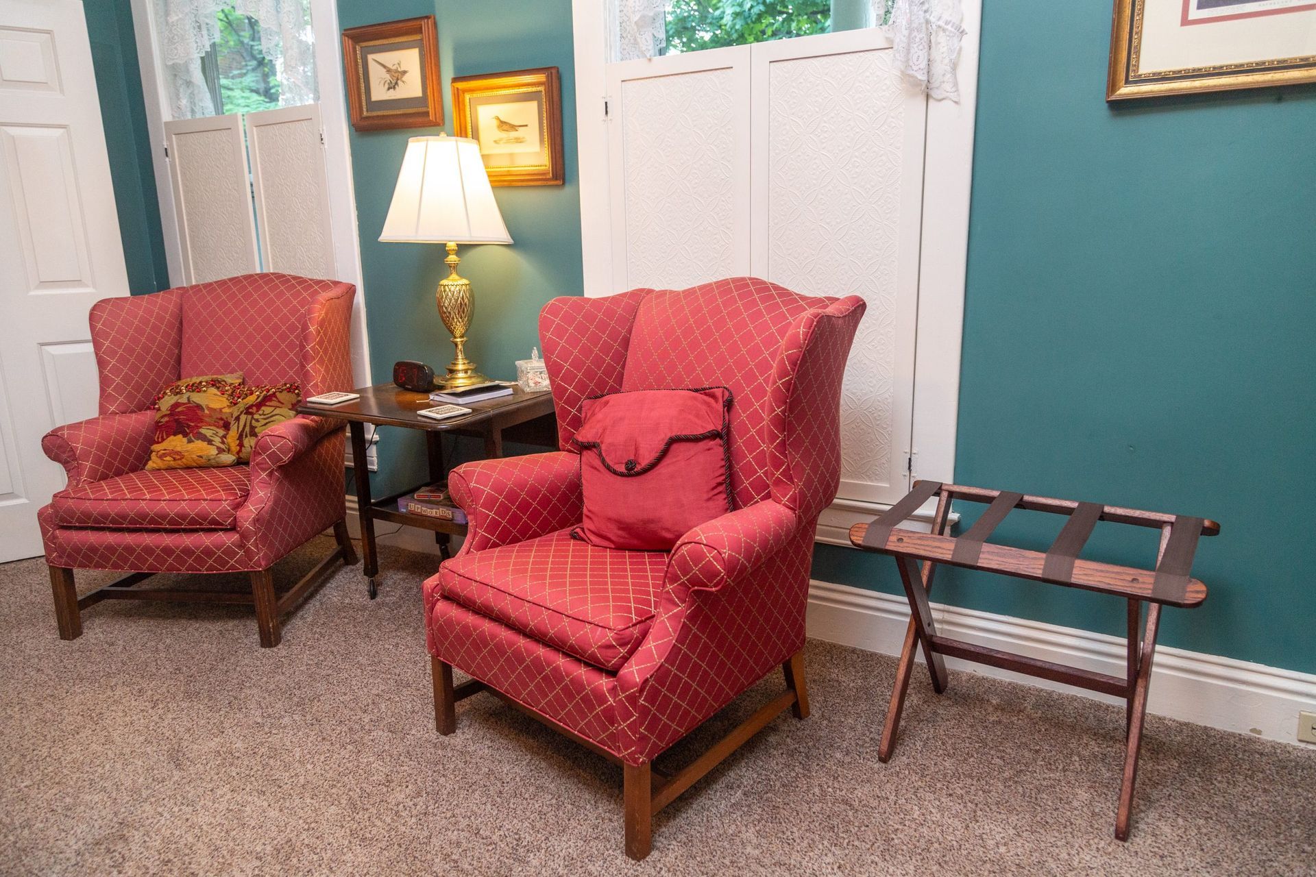 A living room with two red chairs and a luggage rack