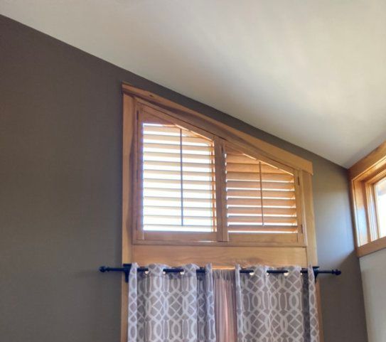 A window with shutters and curtains in a room