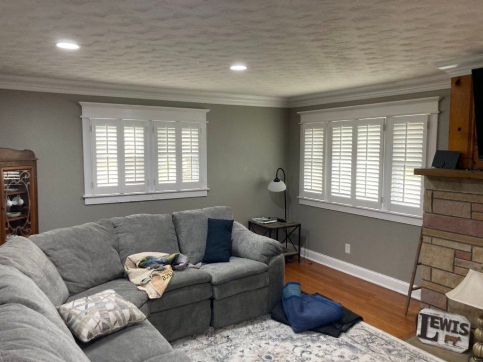 A living room with a couch , fireplace , and shutters on the windows.