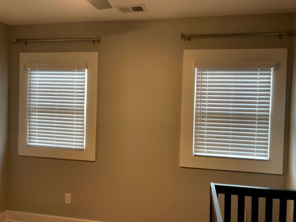 A bedroom with two windows and blinds on them