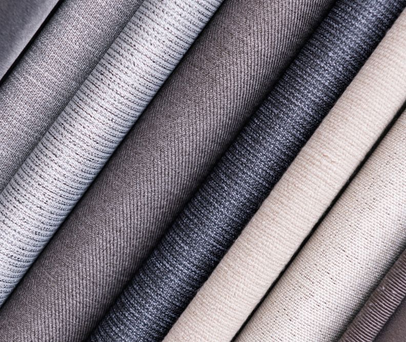 Close-up of fabric swatches in shades of gray and beige, showing various textures.