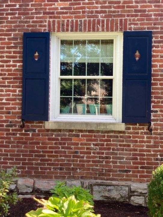 A window with blue shutters on a brick wall