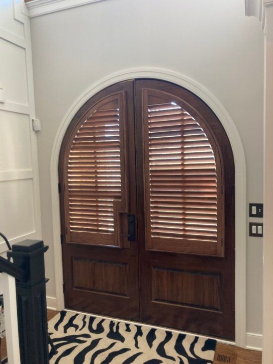 A pair of arched wooden doors with shutters on them