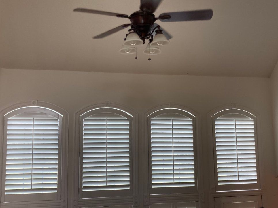 A room with arched windows and a ceiling fan