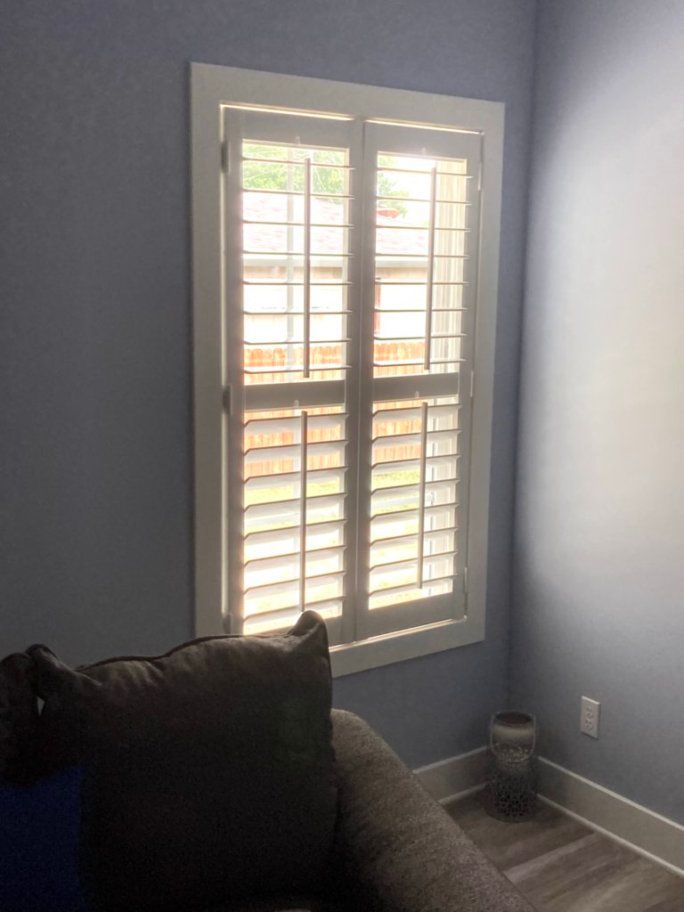 A living room with a couch and a window with shutters