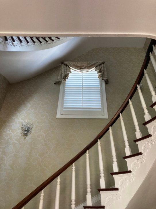 A curved staircase with white railings and a window