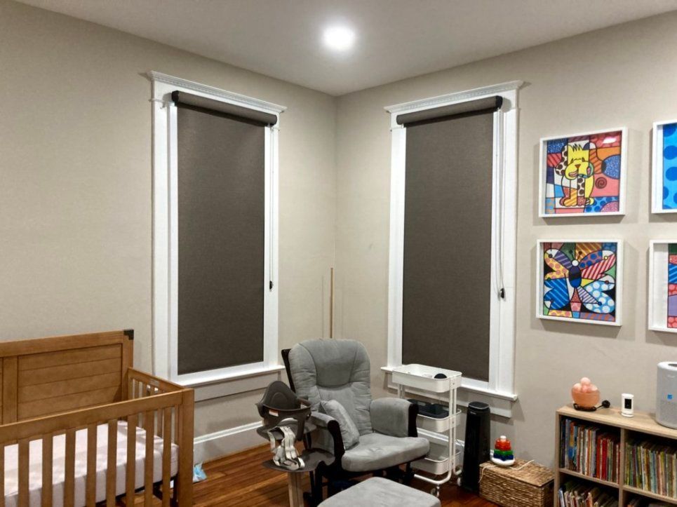 A nursery with a crib , rocking chair , ottoman and bookshelves.