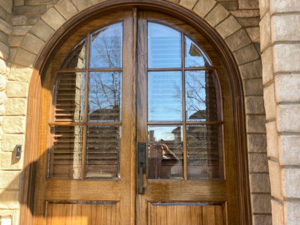 A wooden door with arched windows on a brick building