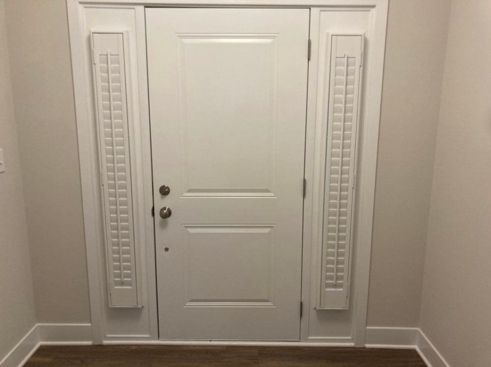 A white door with shutters on the side of it in a hallway.