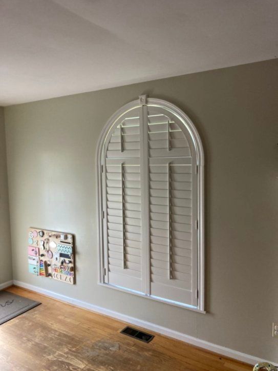 A living room with a large window and shutters on it.