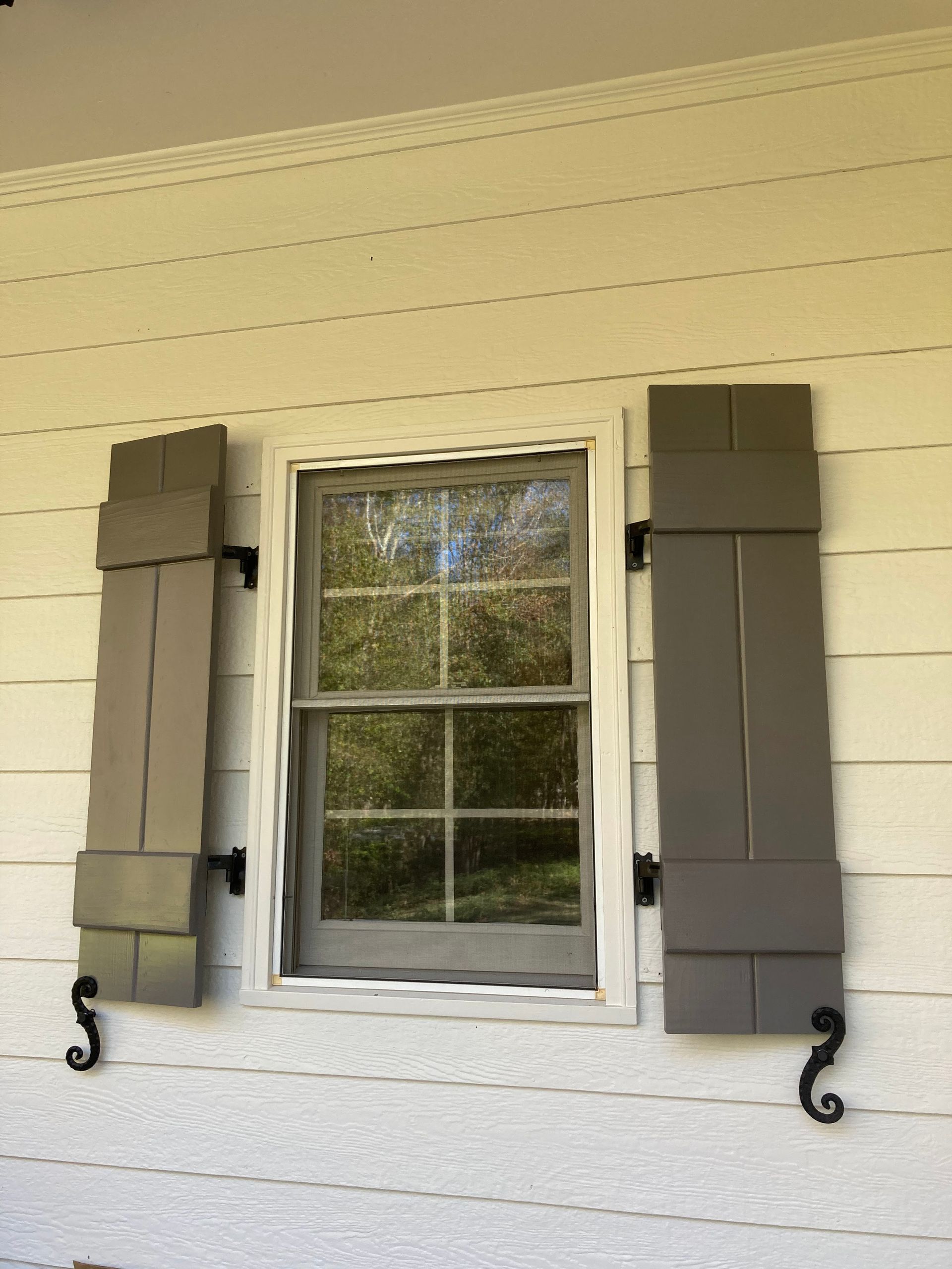 A window with shutters on it is on a white house.