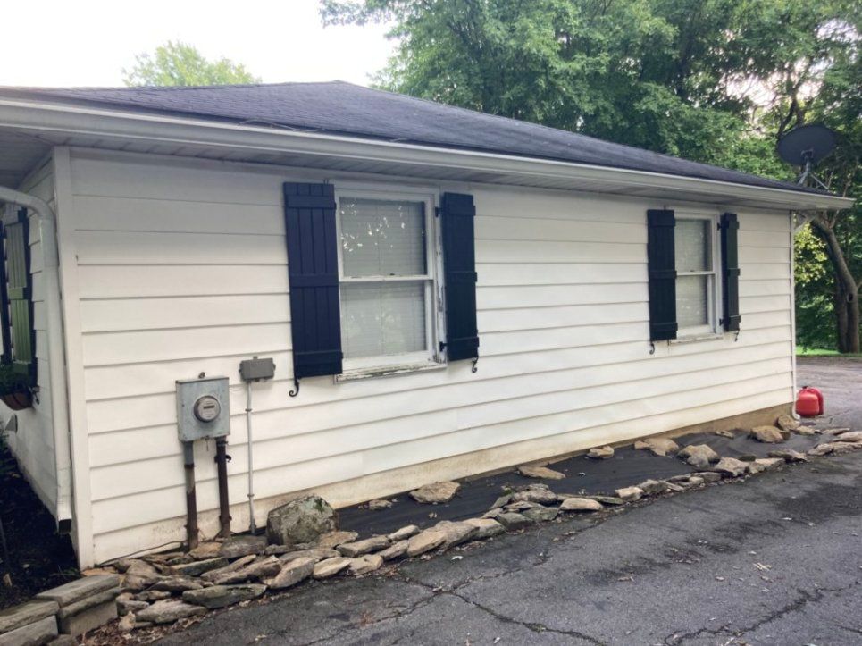 A white house with black shutters on the windows and a black roof.