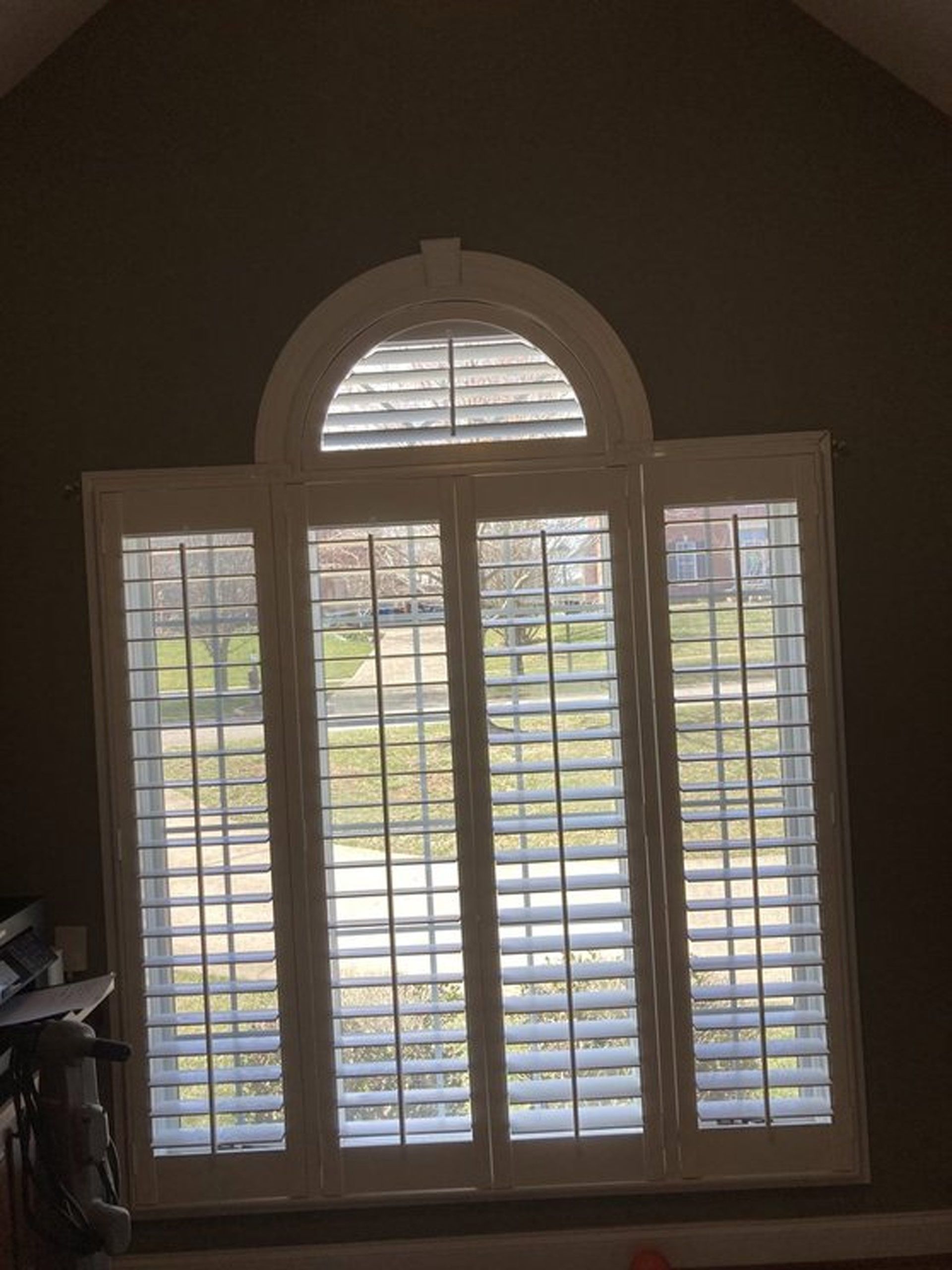 A large window with arched shutters in a living room