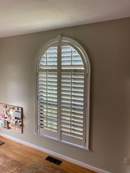A living room with a large window with shutters on it.