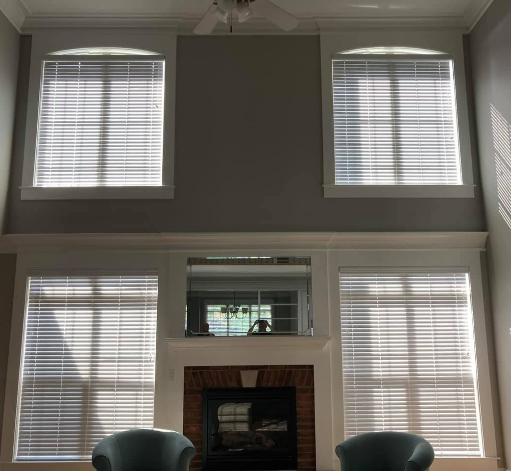Living room with a fireplace and multiple windows, sunlight streaming in.