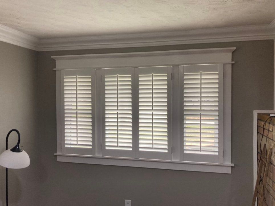 A room with a lamp and a window with shutters on it.