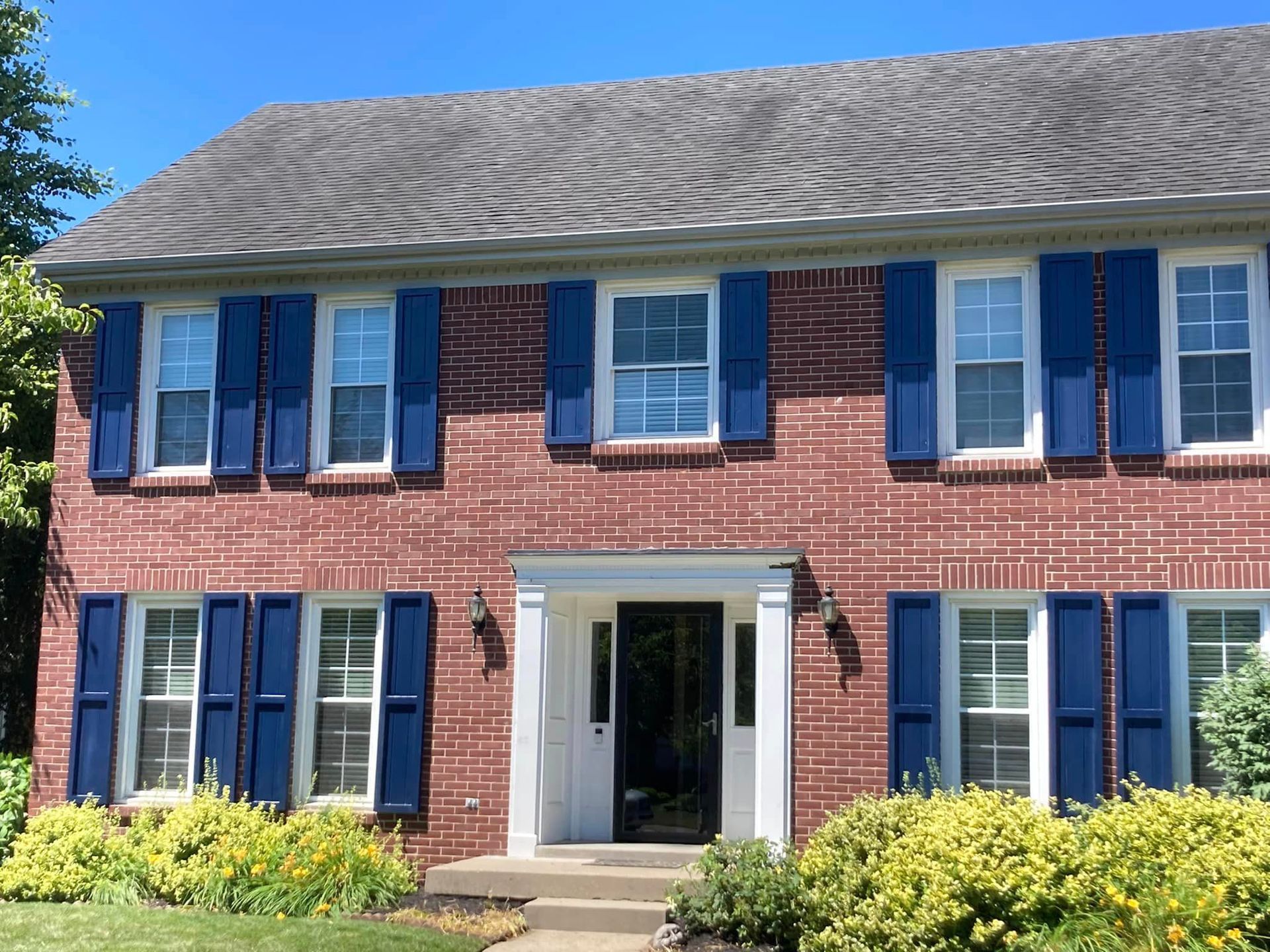 A brick house with blue shutters on the windows