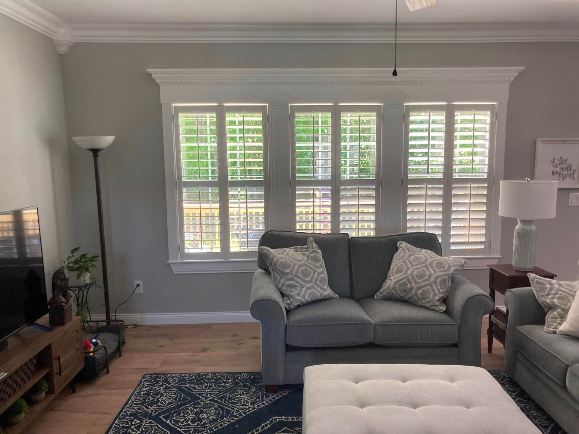 A living room with a couch , ottoman , and television.