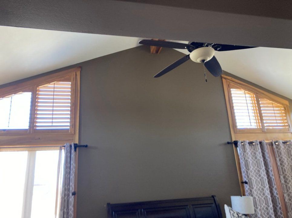A living room with a ceiling fan and shutters on the windows