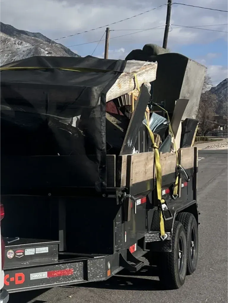 A trailer with a lot of junk on it is parked on the side of the road.