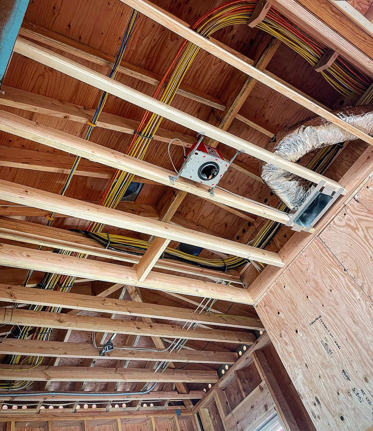 The ceiling of a building under construction has a lot of wires hanging from it
