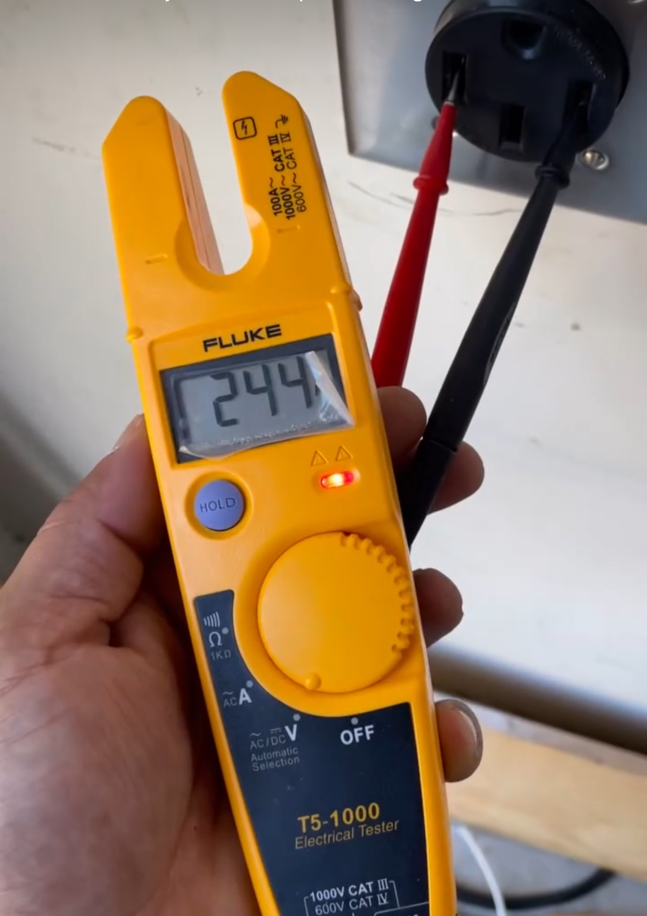 A hand is holding a fluke ts 1005 digital clamp meter