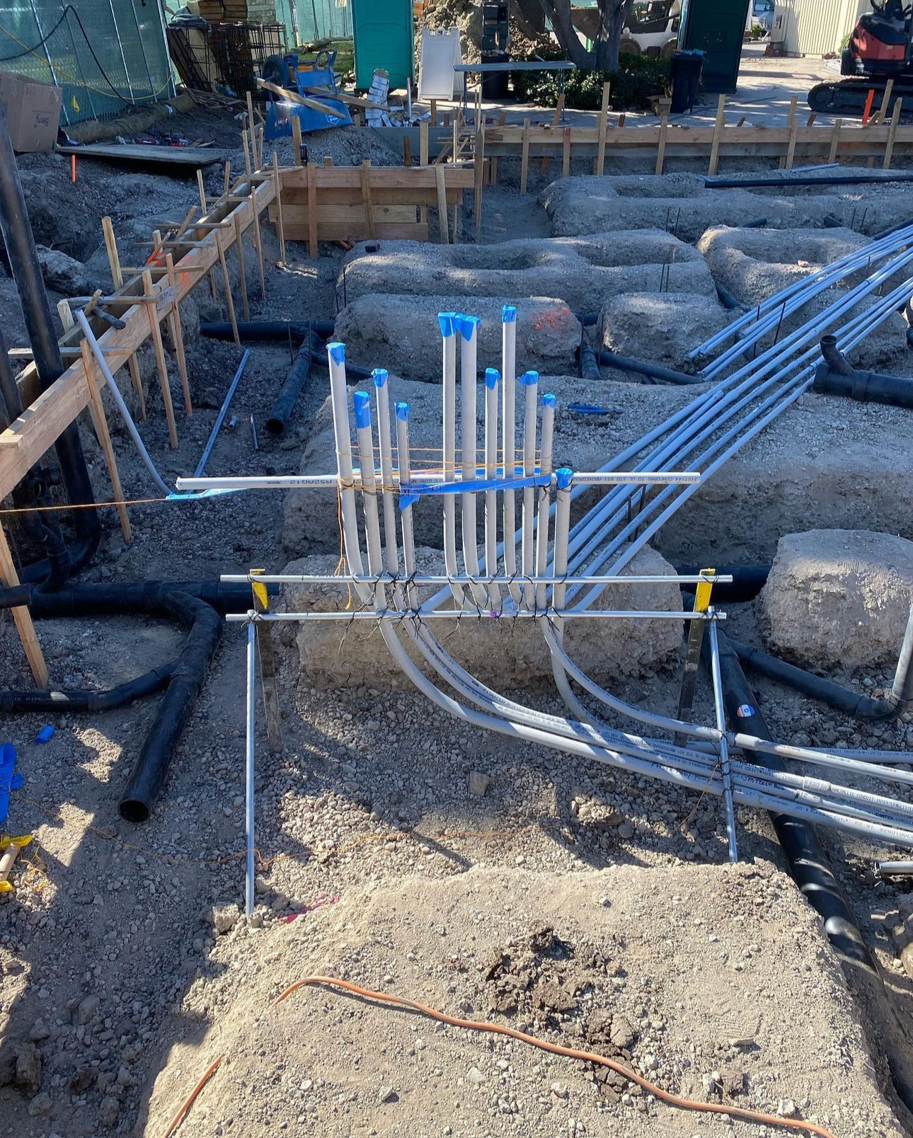 A bunch of pipes are laying in the dirt on a construction site