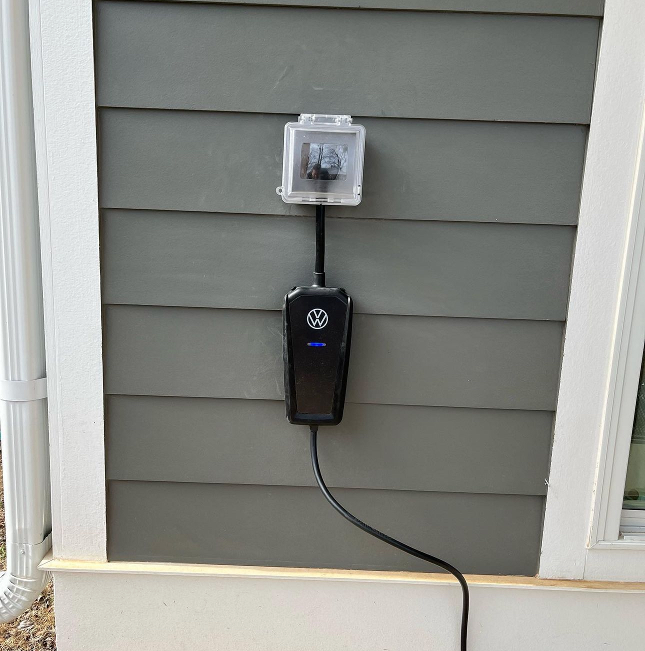 A black device is attached to the side of a house