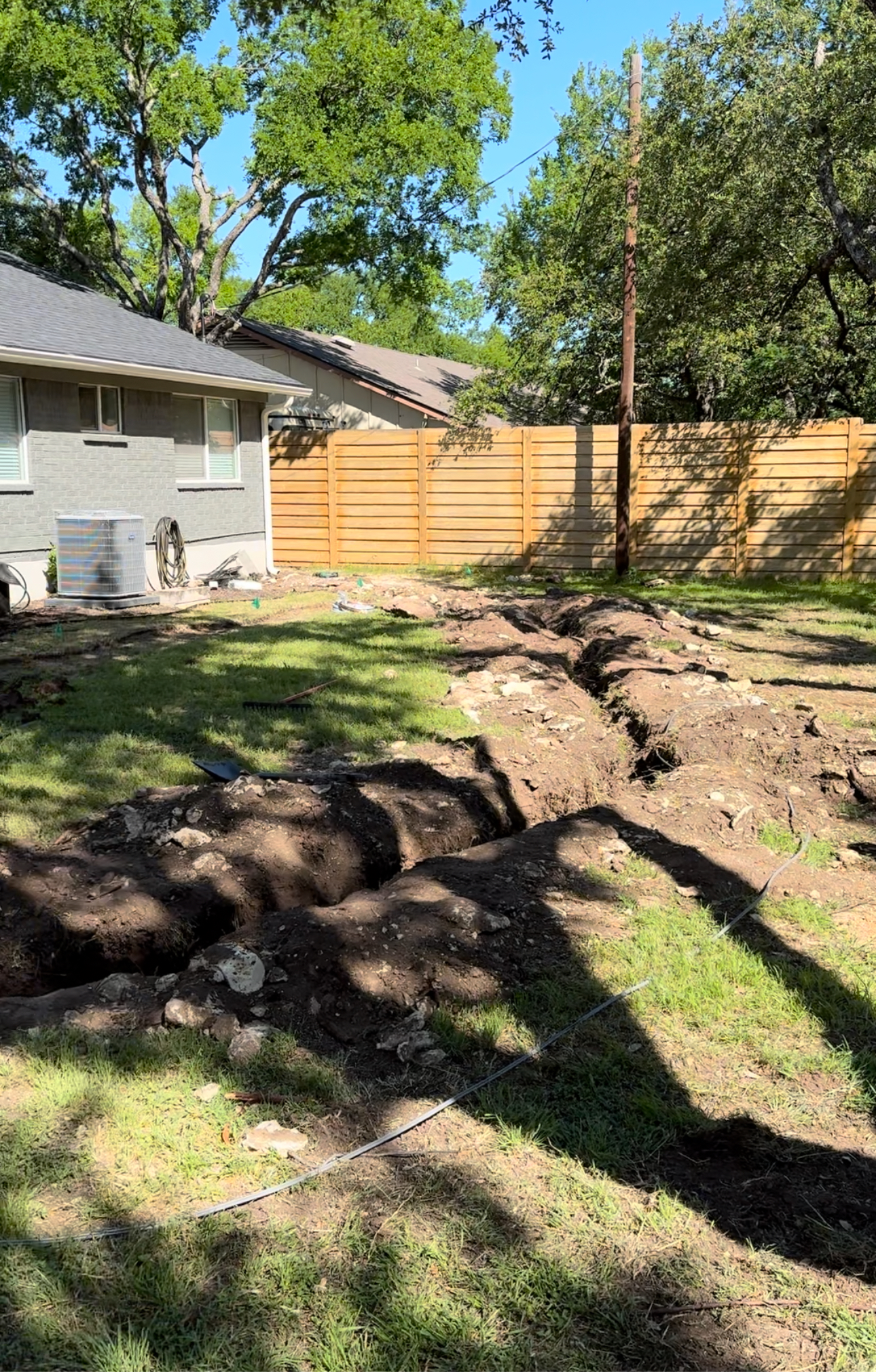 A large pile of dirt is in the backyard of a house.