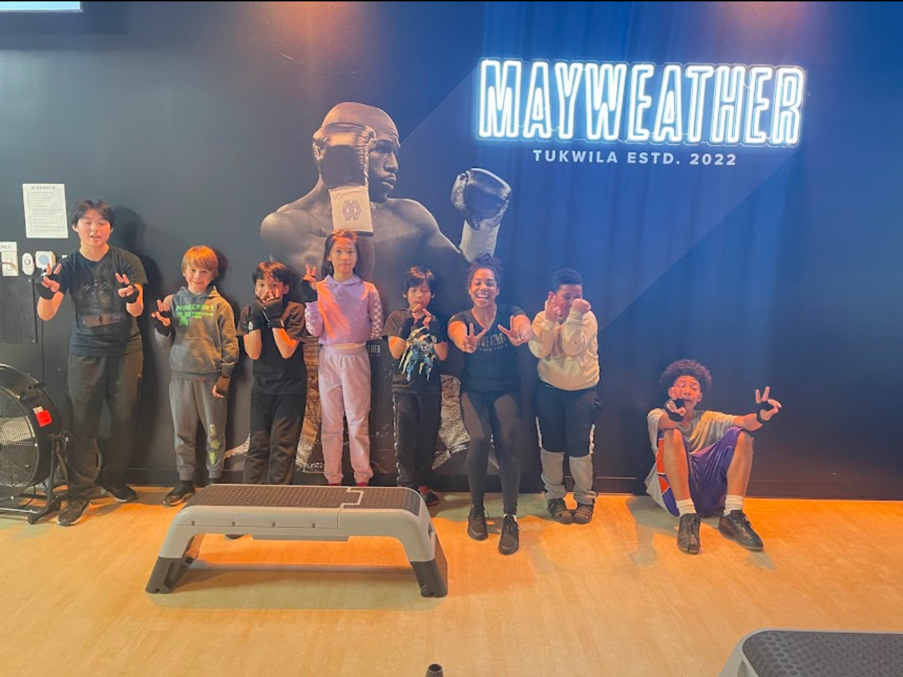 A group of people standing in front of a wall that says mayweather