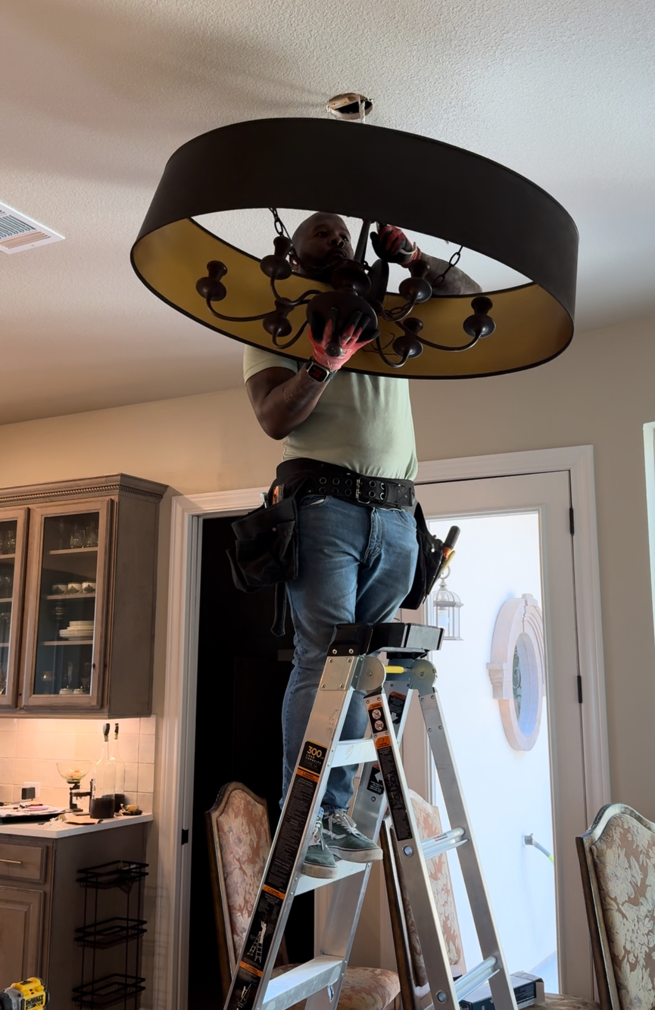 A man on a ladder working on a chandelier