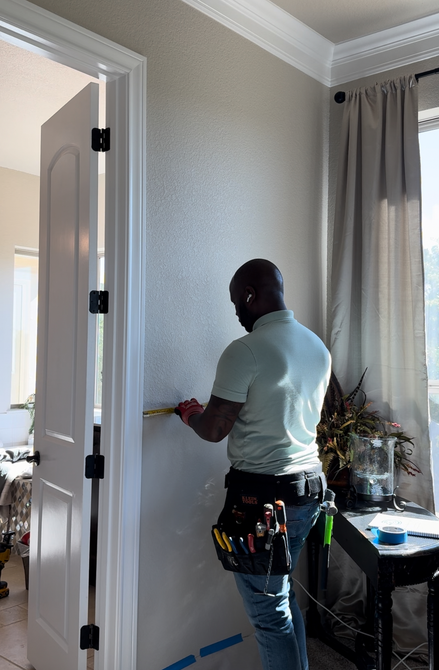 A man measuring a wall with a tape measure