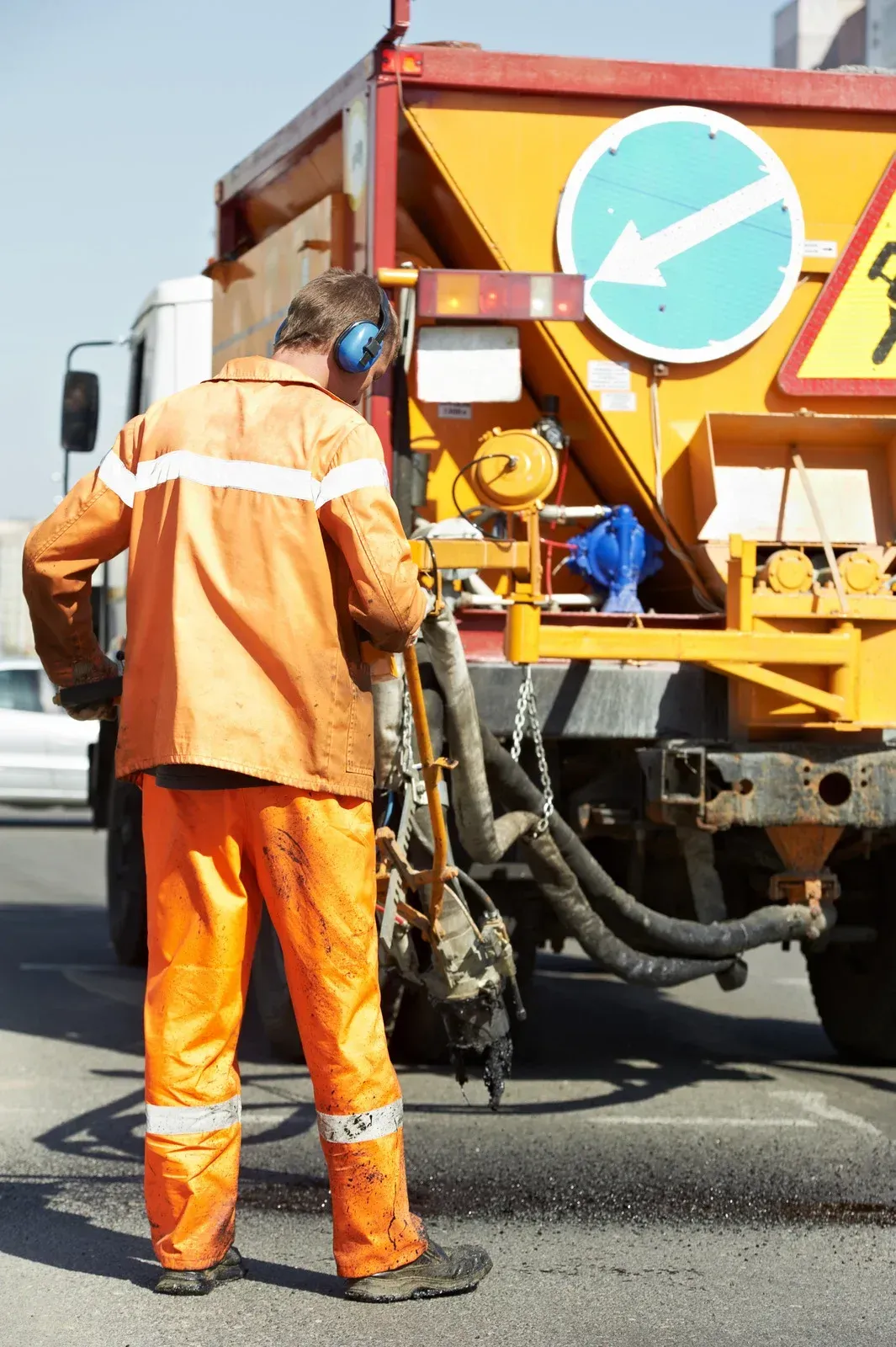 A man in orange pants is standing in front of a truck.