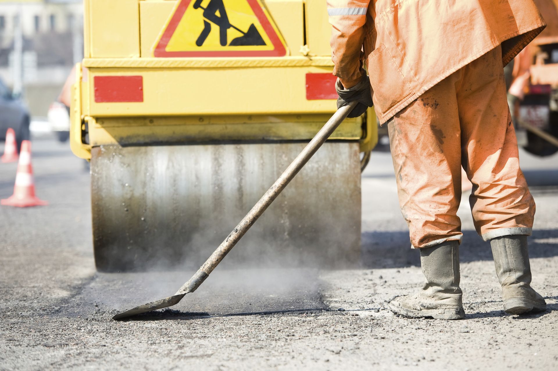 A man is working on a road with a yellow truck in the background