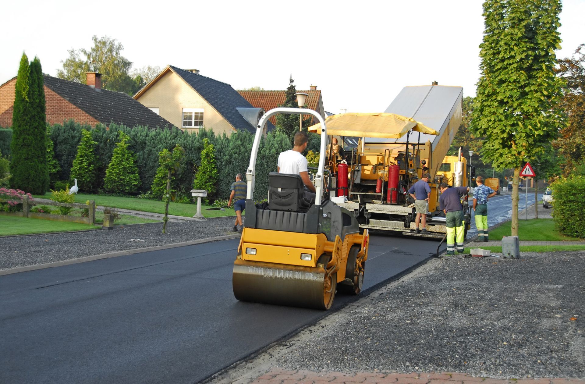 A man is driving a yellow roller on a road
