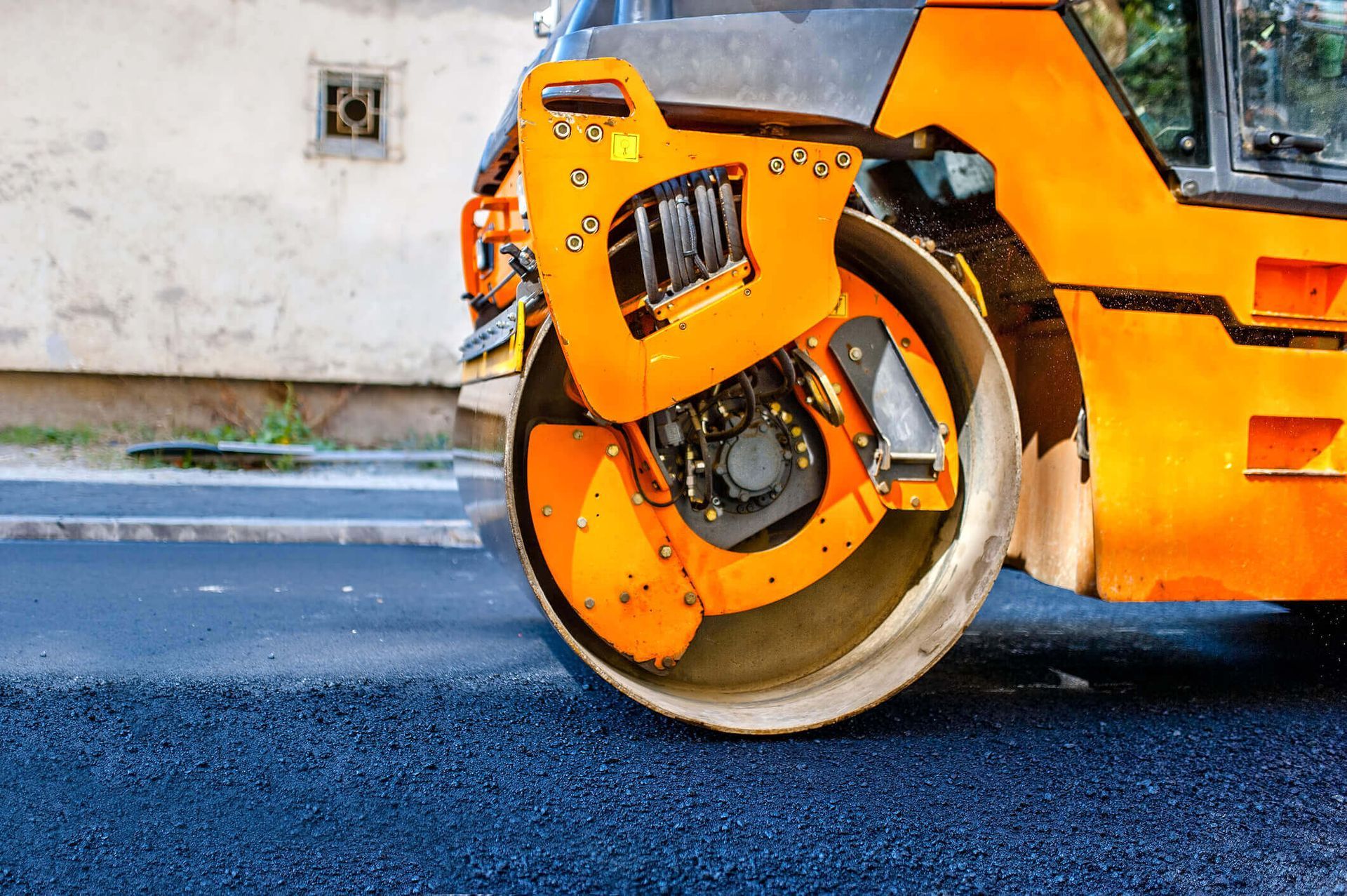 A yellow and black roller is rolling asphalt on a road.
