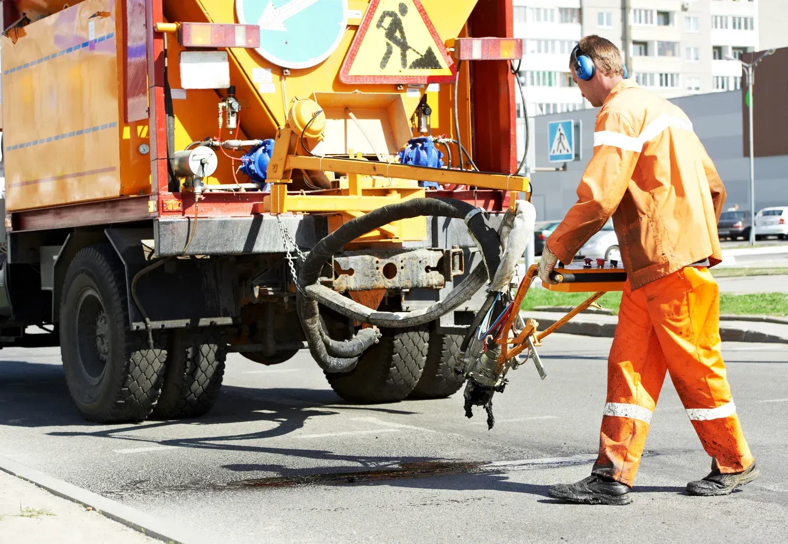A man in orange pants is standing in front of a truck.