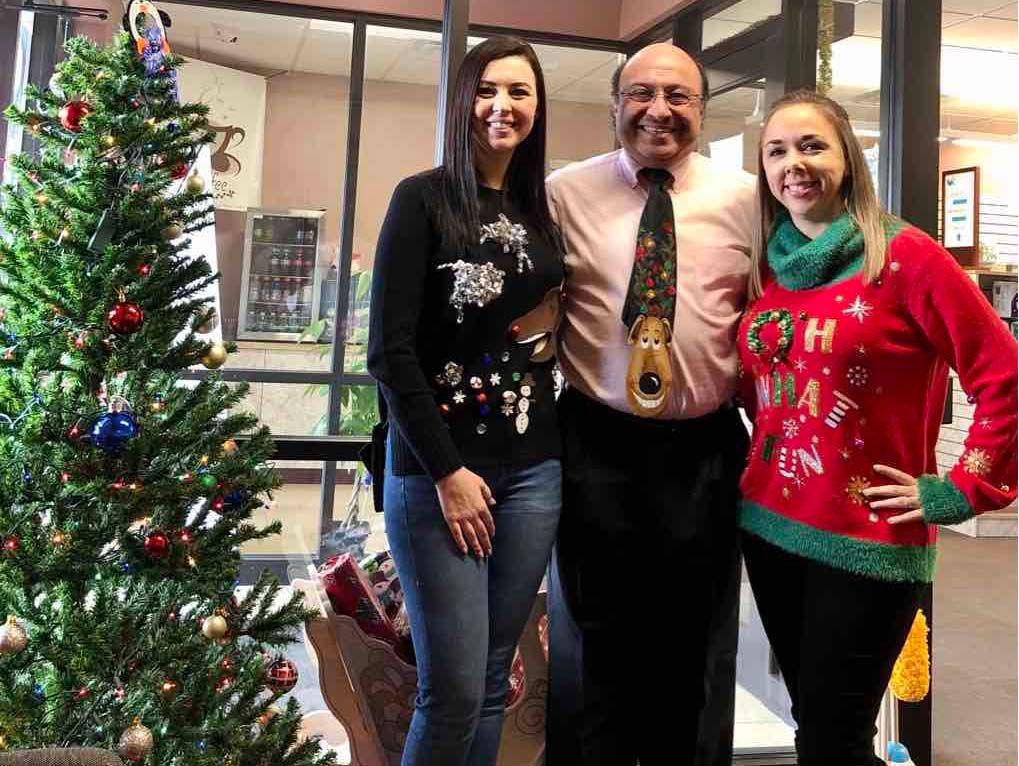 Three people posing beside a decorated Christmas tree indoors
