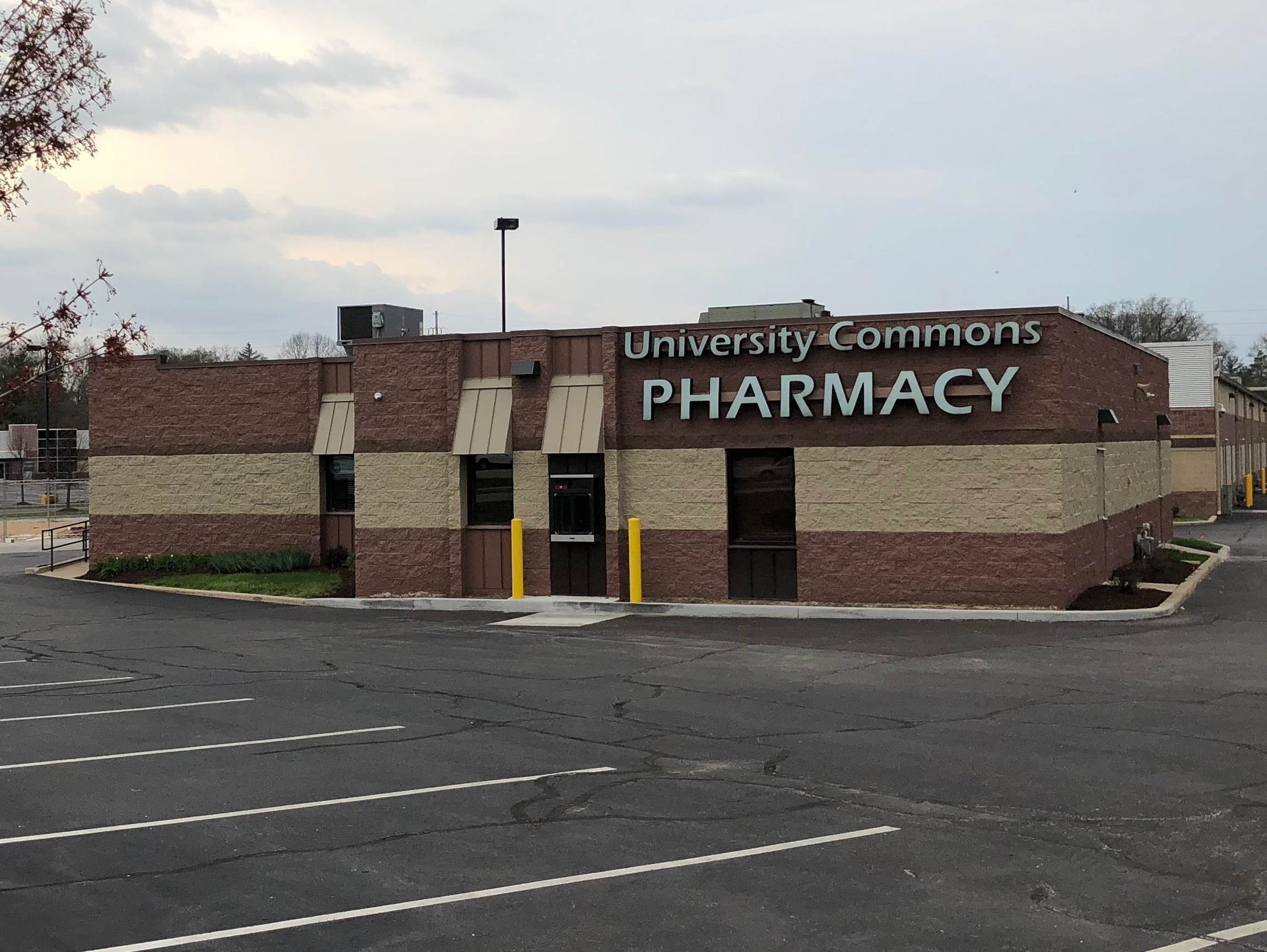 University Commons Pharmacy brick building with parking lot in front