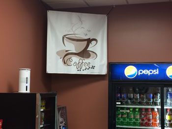 Coffee sign above a Pepsi cooler in a small shop